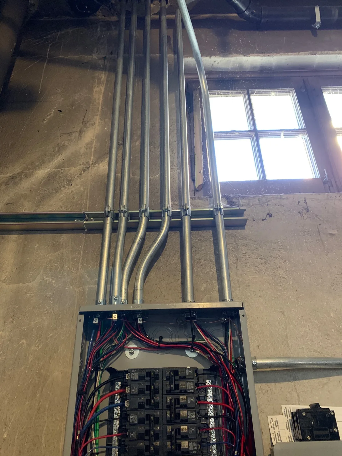 Interior breaker panel with neatly bent EMT conduit runs during the electrical restoration